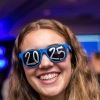 A grad smiles wearing 2025 glasses